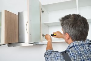 Middle-aged Man Installing Cabinet Door during Kitchen Remodel